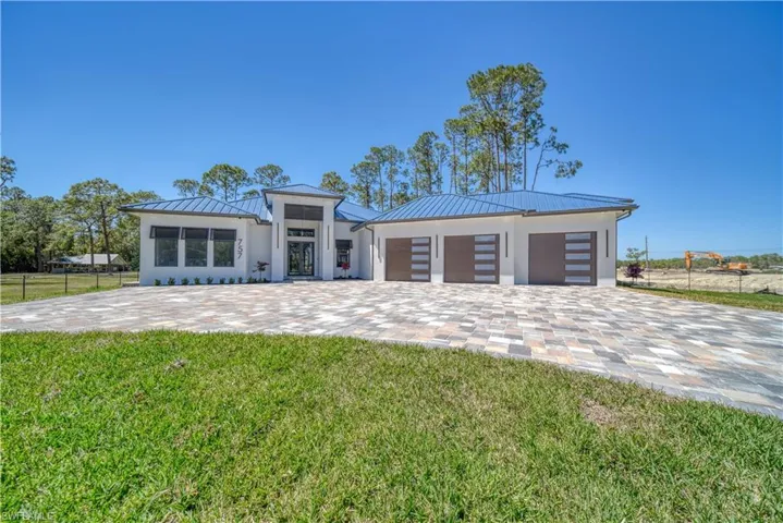 Modern home featuring metal roof, paver driveway, 3 car Garage and a front yard