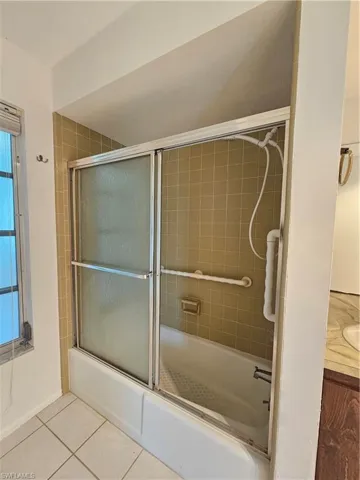 Spa-inspired ensuite bath featuring a frameless glass shower enclosure with dual sliding doors, tile surround, grab bars for accessibility, and ceramic tile flooring