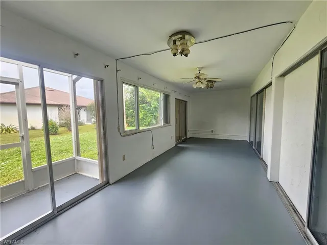 Expansive screened enclosure with gray flooring, multiple windows, and sliding glass doors
