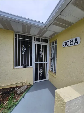 Entryway featuring a security screen door, security window bars, and a painted concrete porch