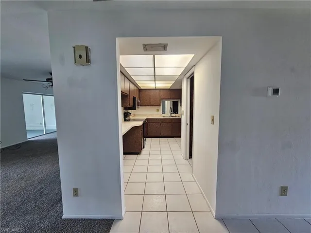 Kitchen featuring wood-finish cabinetry, white countertops, a built-in range hood, and tile flooring