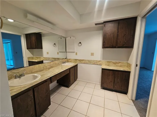 Dual basin vanity with stone-finish countertop, integrated mirror, and wood-finish cabinetry