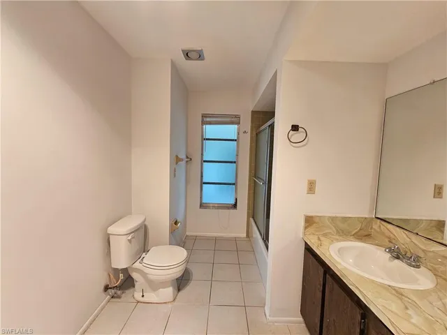Bathroom featuring a single vanity with a decorative countertop, an integrated sink, and a framed mirror