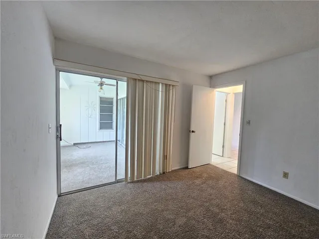 Carpeted room with sliding glass doors, a ceiling fan, and an additional room with a ceiling fan