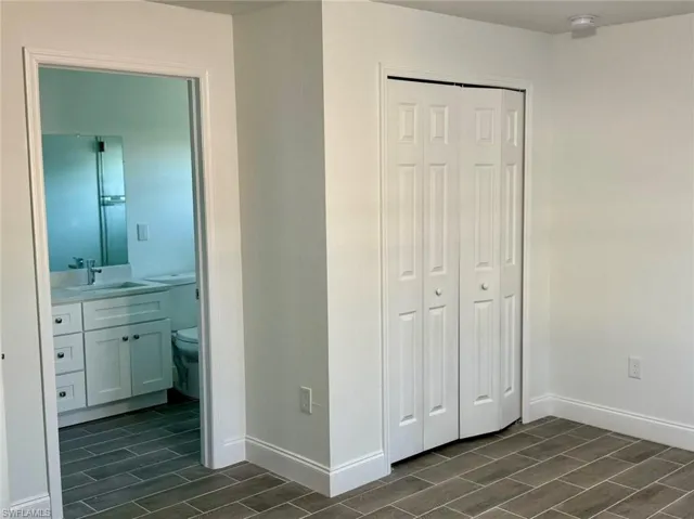 Unfurnished bedroom featuring ensuite bath, a closet, and sink
