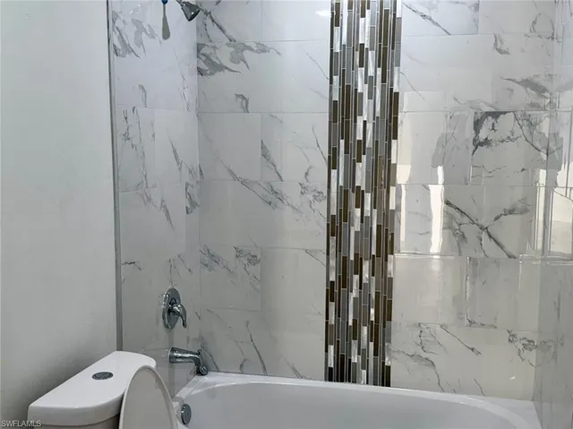 Bathroom with tiled shower / bath combo and toilet