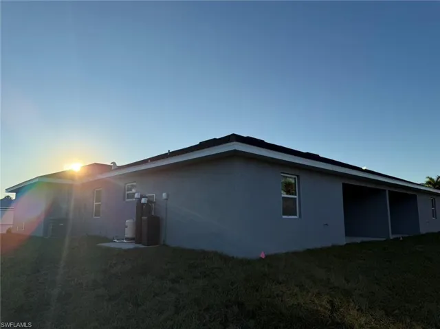 Property exterior at dusk with a lawn and central AC