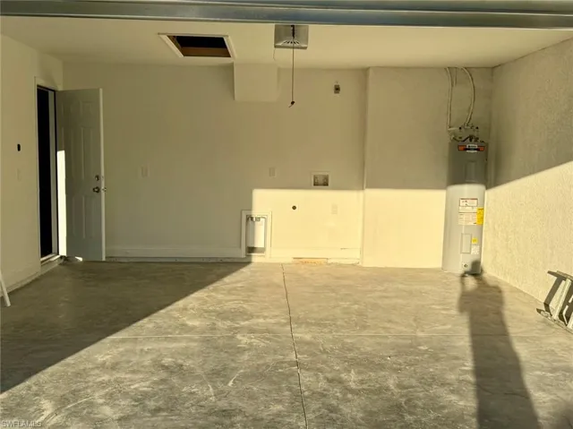 Garage featuring electric water heater and a garage door opener