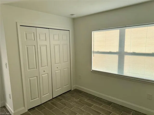 Unfurnished bedroom featuring dark hardwood / wood-style flooring and a closet