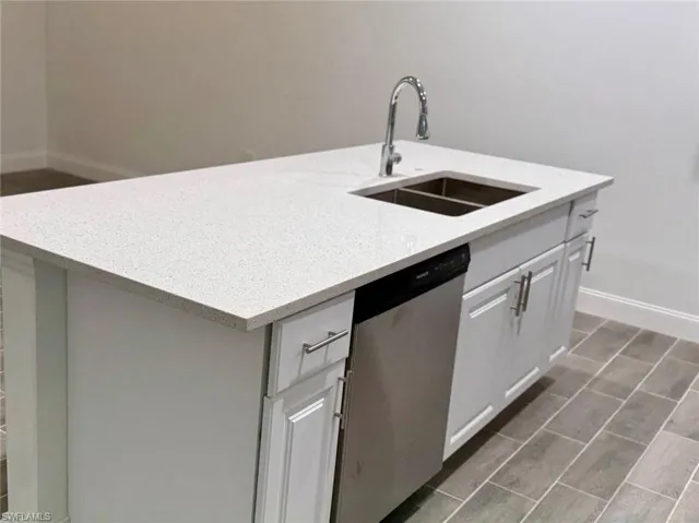 Kitchen with white cabinetry, dishwasher, a center island with sink, and sink