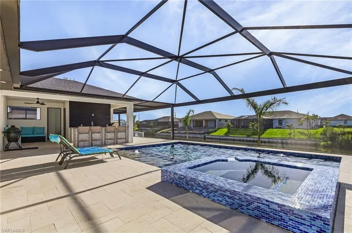 View of pool with an in ground hot tub, glass enclosure, a patio area, and ceiling fan