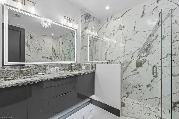 Bathroom with dual vanity, an enclosed shower, tile walls, and tile patterned floors