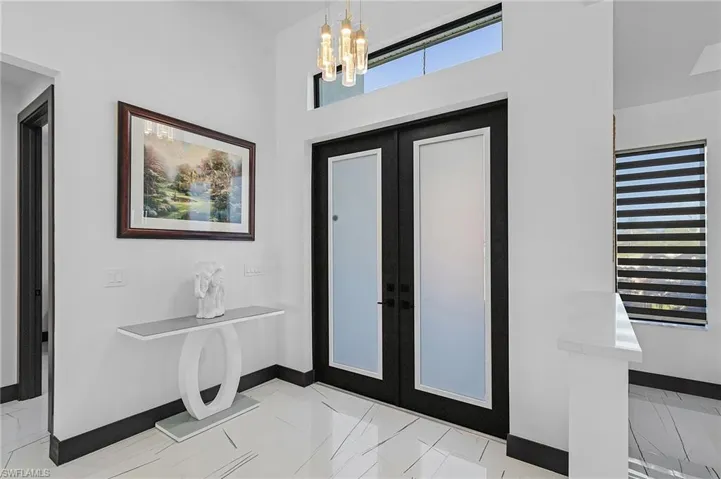 Foyer entrance with light tile patterned flooring, french doors, and a chandelier