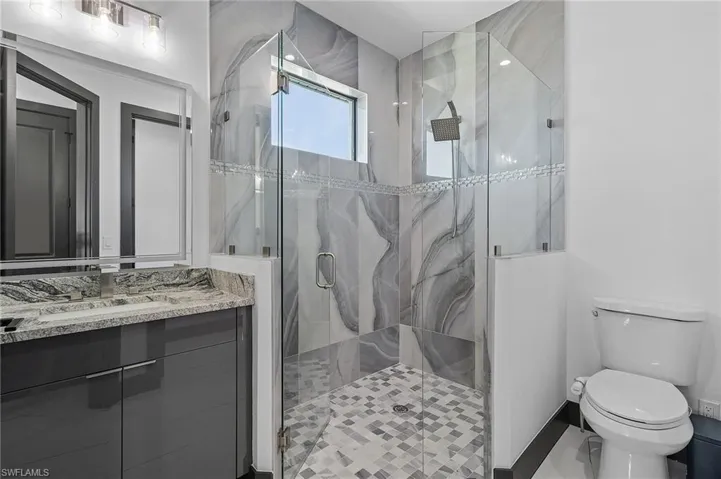 Bathroom featuring tile patterned flooring, a shower with shower door, toilet, and vanity