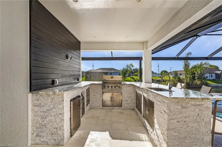 View of patio with sink, an outdoor kitchen, a lanai, and grilling area