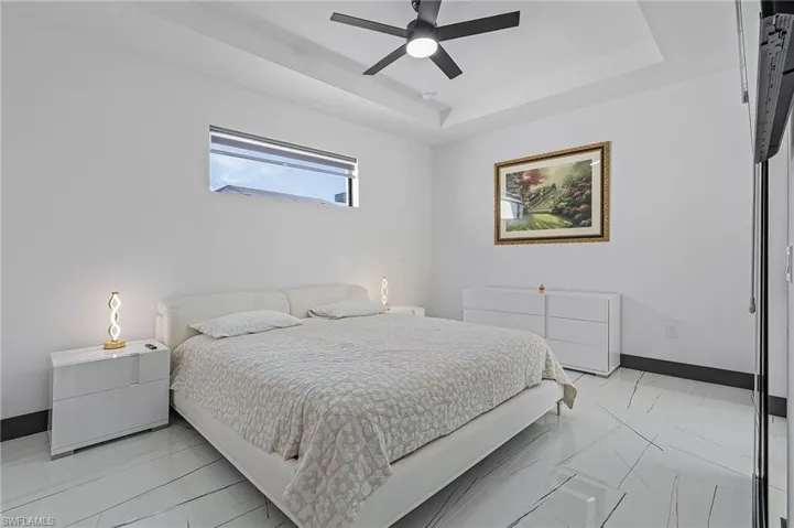Bedroom featuring light tile patterned flooring, a raised ceiling, and ceiling fan