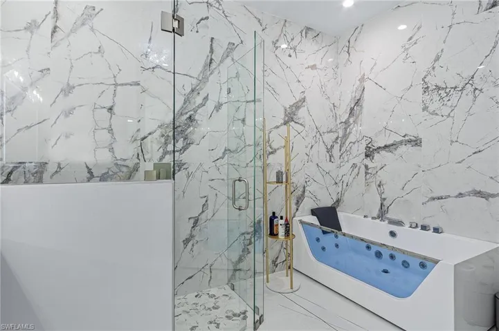 Bathroom with a shower with door, tile patterned flooring, and tile walls