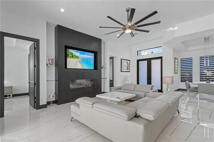 Tiled living room with ceiling fan and french doors