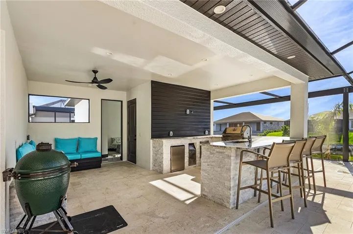 View of patio with area for grilling, an outdoor living space, ceiling fan, and a bar