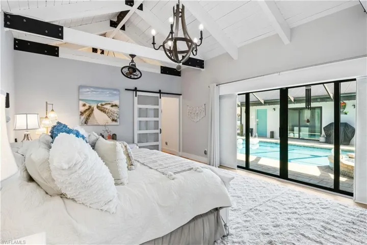 Master bedroom has its own private wing and is a neutral palette of soothing tones and textiles - hickory hardwood flooring, soaring vaulted ceilings, chandelier lighting, large white beams accented with iron hardware and a barn style door to the master closet. Easy access to the outside pool area as well!