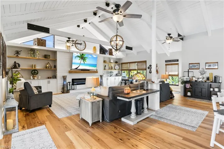 A MASSIVE focus wall showcases the wide open great room with soaring vaulted ceilings, custom wood beams with large height and volume and natural light abounds. Tasteful and custom cabinets and shelving along with a decorative fireplace add the perfect finishing touches!