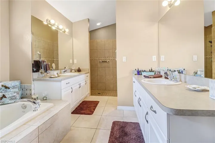 Bathroom featuring vanity, independent shower and bath, lofted ceiling, and tile patterned flooring