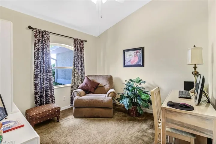 Living area featuring lofted ceiling, carpet floors, and ceiling fan