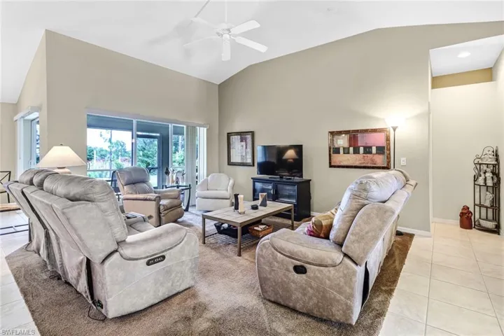 Living room featuring lofted ceiling, ceiling fan, and light tile patterned floors