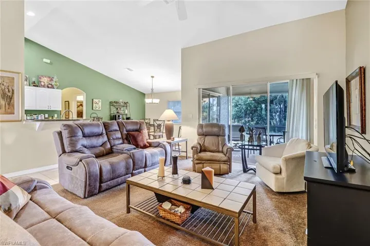 Living room featuring light colored carpet, high vaulted ceiling, and ceiling fan