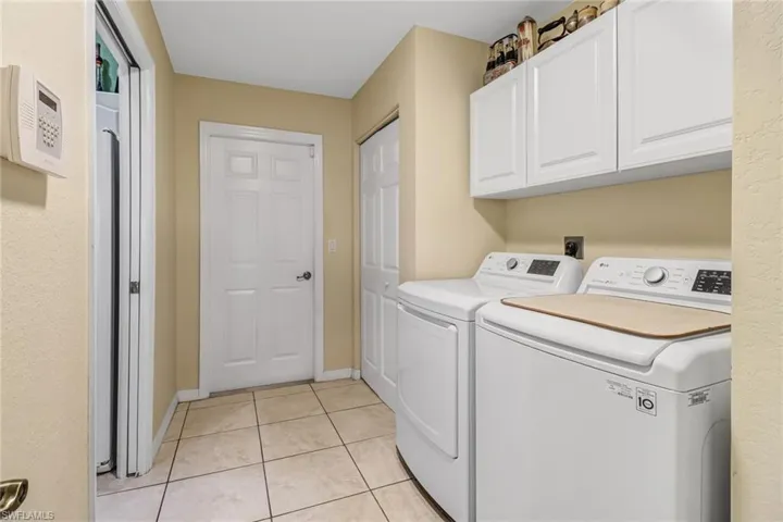 Washroom with cabinets, light tile patterned flooring, and washing machine and clothes dryer