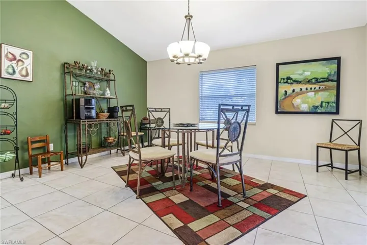 Tiled dining space with lofted ceiling and a notable chandelier