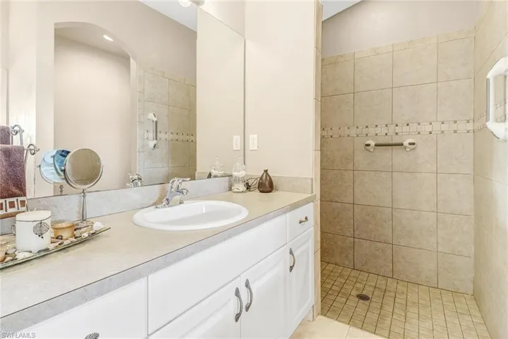 Bathroom with vanity, a tile shower, and tile patterned flooring