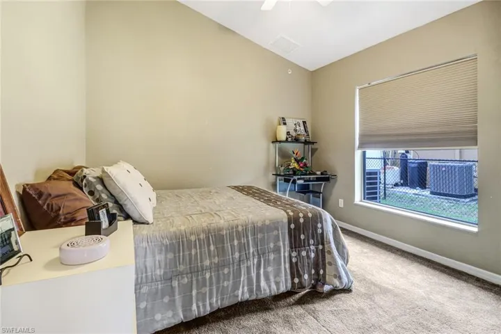 Carpeted bedroom featuring vaulted ceiling and ceiling fan