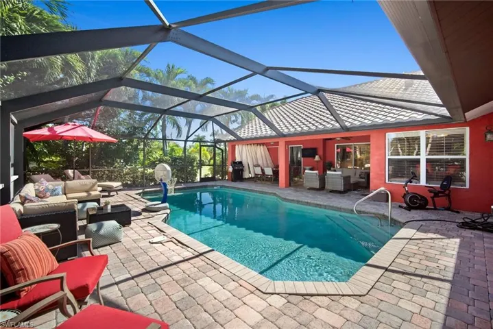 Swimming pool with an outdoor living space, glass enclosure, a patio, a sunroom, and a grill