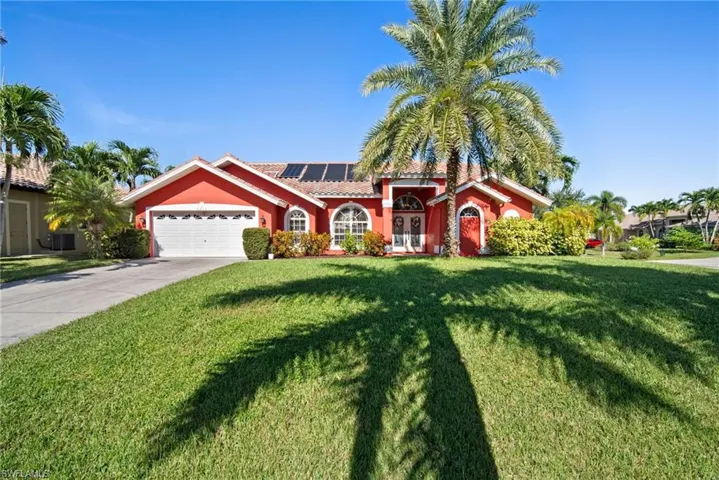 Mediterranean / spanish home featuring solar panels, a front yard, driveway, stucco siding, and an attached garage