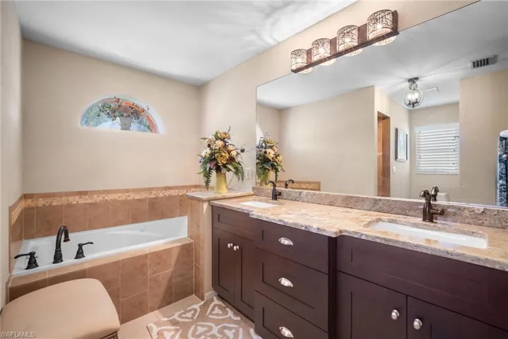 Full bathroom featuring double vanity, a bath, healthy amount of natural light, and light tile patterned floors