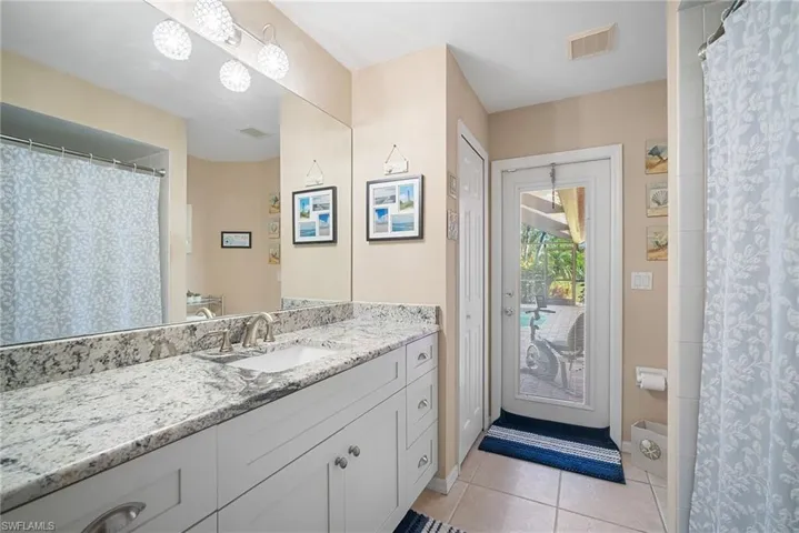 Bathroom with a shower with curtain, light tile patterned floors, and vanity