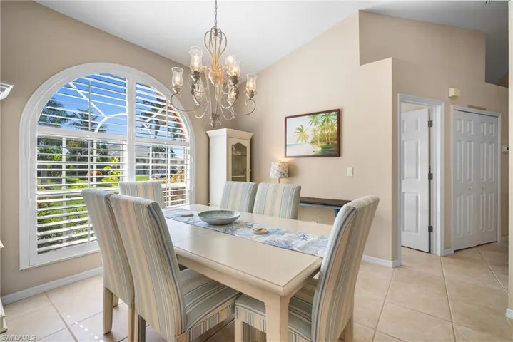 Dining area with light tile patterned floors, a chandelier, and lofted ceiling