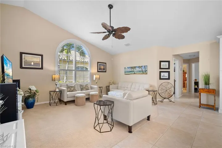 Living area with a ceiling fan, high vaulted ceiling, and light tile patterned floors