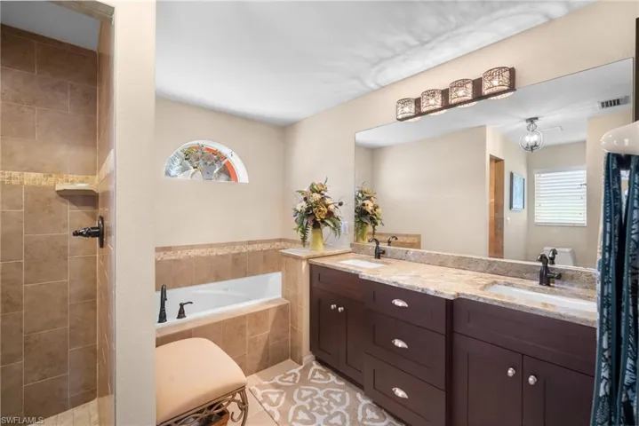 Bathroom with a garden tub, double vanity, healthy amount of natural light, and a tile shower