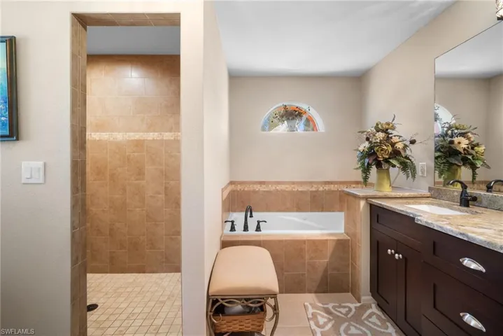 Bathroom featuring a bath, vanity, light tile patterned floors, and tiled shower
