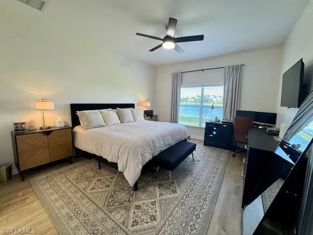 Spacious bedroom featuring wood-finish flooring and a contemporary ceiling fan