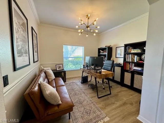 Spacious room featuring light wood-finish flooring, crown molding, and a modern sputnik-style chandelier