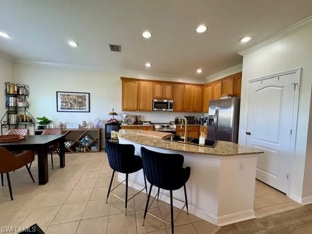 Kitchen with crown molding, sink, an island with sink, and appliances with stainless steel finishes