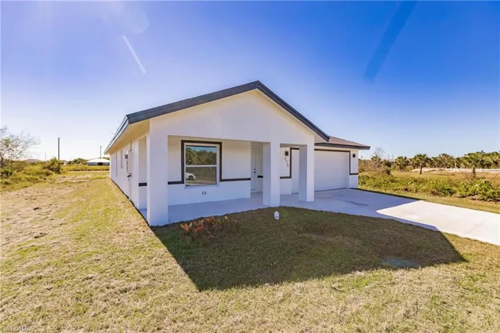 Modern farmhouse with driveway, a garage, stucco siding, and a front lawn