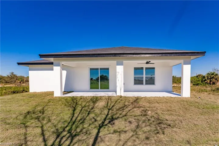 Back of house with ceiling fan, a patio, a yard, and stucco siding