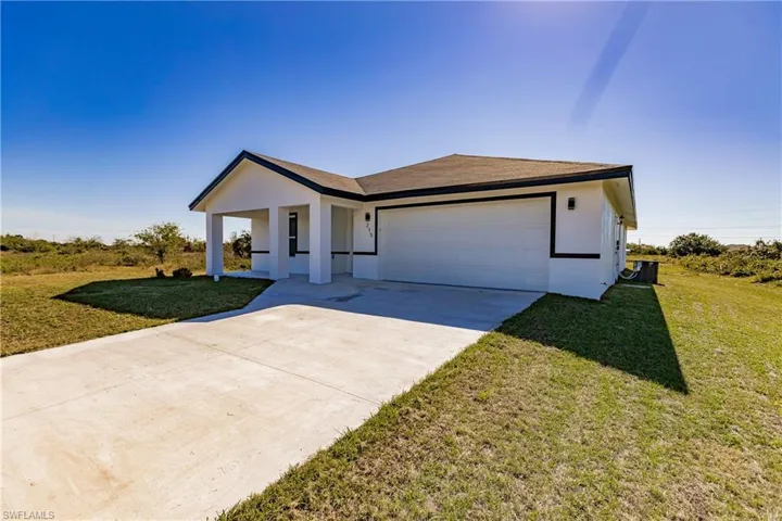 View of front of home with driveway, a front lawn, an attached garage, and stucco siding