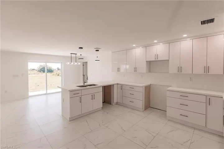 Kitchen with recessed lighting, light marble finish floors, a peninsula, and white cabinets