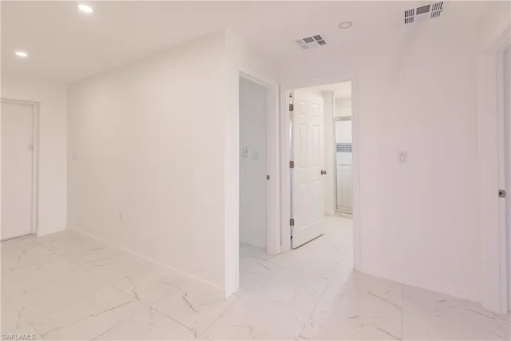 Hallway with light marble finish flooring and recessed lighting