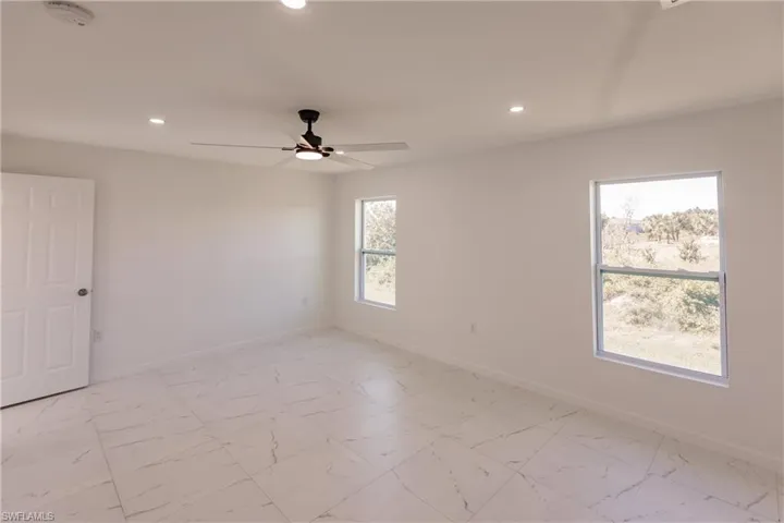 Unfurnished room with a smoke detector, recessed lighting, ceiling fan, and light marble finish floors